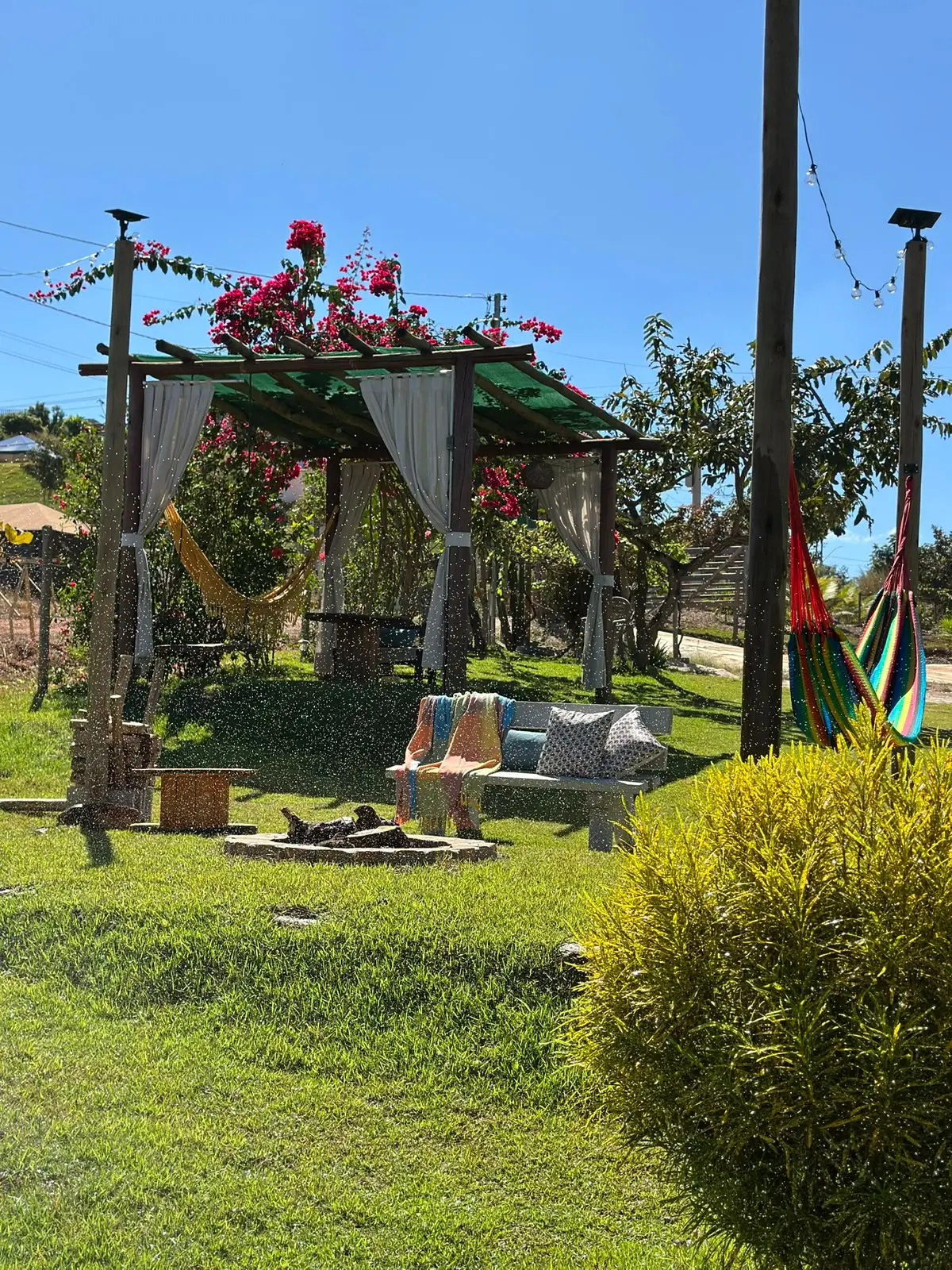 Pergolado com redes coloridas e jardim ensolarado